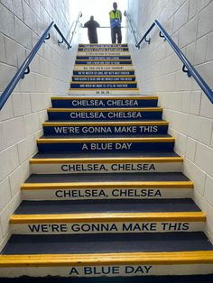 blue and yellow stairs with the words chelsea on them in different languages, along with two men standing at the top