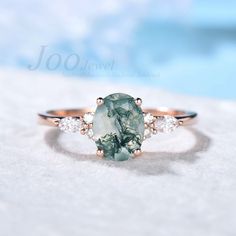 an oval cut green and white diamond ring with three stone accents on the band, set in 18k rose gold