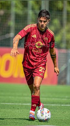 a soccer player is running with the ball in his hand while wearing red and gold