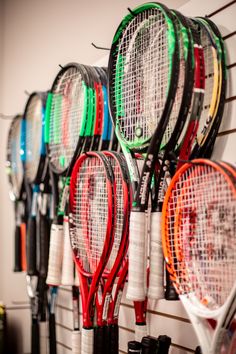 there are many tennis rackets hanging on the wall