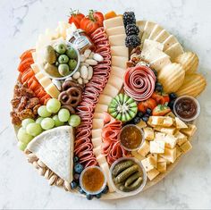 a platter filled with cheese, crackers, olives, and other snacks