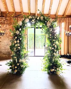 an archway decorated with white flowers and greenery