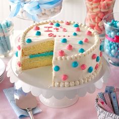 a table topped with a cake covered in white frosting and lots of blue and pink sprinkles