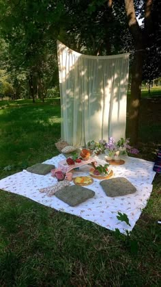 a blanket on the ground with plates and bowls sitting on it in front of a tree