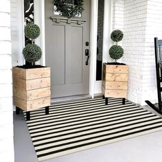 two wooden planters sitting on the front porch next to a white door with black and white stripes