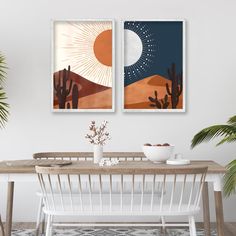 two paintings hanging on the wall above a dining room table with cactus and desert scene