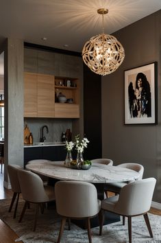 a dining room table with white chairs and a chandelier hanging from the ceiling