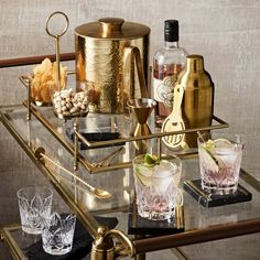 a bar cart filled with drinks and liquors on top of a glass table next to a wall