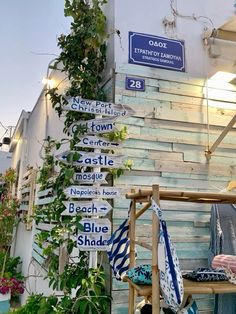 several street signs in front of a building with plants growing up the side of it