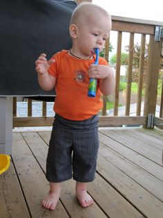 a toddler standing on a deck with a toothbrush in his mouth