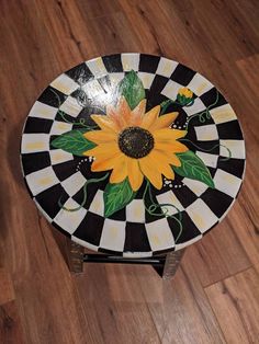 a black and white checkered table with a yellow sunflower painted on the top