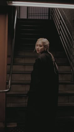 a woman standing at the bottom of an escalator