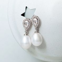 Classic Pearl Dangle earrings crafted with cubic zirconia crystals and ivory freshwater pearls. These dainty drops are a timeless style, perfect for your wedding day. .925 Sterling Silver Cubic Zirconia pave crystals Ivory Fresh Water Pearls, the shapes in natural pearls can vary Hypoallergenic post Height: 0.8in (2 cm) x Width: 0.3in (8mm) #E387