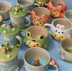 there are many ceramic cups and mugs with animals on them, all decorated in different colors