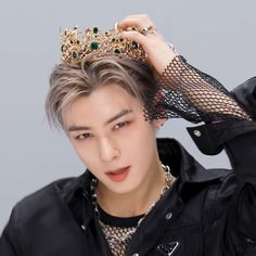 the young man is wearing a black shirt and has a gold crown on his head