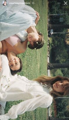 two women in white dresses are laying on the grass