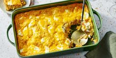 a green casserole dish with a spoon in it next to some wine glasses