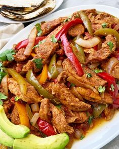 a white plate topped with meat and veggies next to tortilla chips