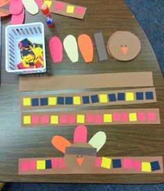 a wooden table topped with paper cut out of turkeys and strips of construction paper