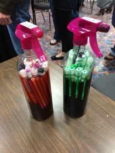 two bottles filled with different colored pens on top of a table