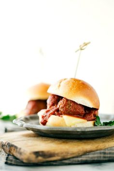 two meatball sandwiches on a plate with toothpicks