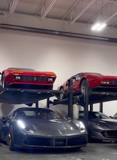 three cars are stacked on top of each other in a garage with two lifters