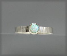 This is just beautiful. A 5mm simulated opal is set into a beautifully hammered sterling silver ring. The hammering is done with a specialty hammer and gives the sterling silver band lots of character and it simply sparkles in the light and the opal will not allow the silver to outdo it. You will be amazed at its beauty. Ring is custom made. Allow 5 days for me to make this ring. It will be shipped no later than six days after ordering. Visit our shop for more special items. capturedillusions.et White Opal Engagement Ring, Opal Ring Silver, Silver Pinky Ring, Sterling Silver Opal Ring, Opal Solitaire Ring, Bridesmaid Rings, Silver Opal Ring, Opal Engagement Ring, Opal Engagement