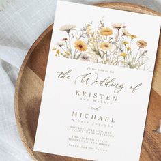 the wedding stationery is displayed on a wooden plate