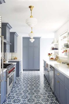 a kitchen with blue cabinets and white counter tops, gold accents on the lights above the stove