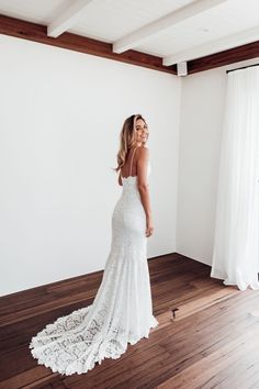 a woman in a white wedding dress standing on a wooden floor and looking off into the distance