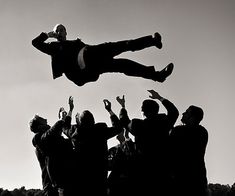 a person jumping in the air with their arms up while people are standing around him