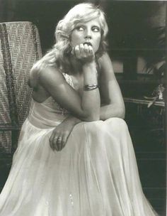 an old photo of a woman sitting on a chair with her hand under her chin