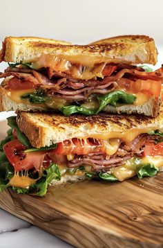 a sandwich with ham, cheese and tomatoes on a cutting board