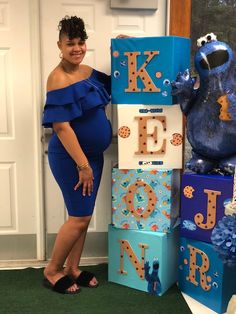 a pregnant woman standing next to blocks that spell out the letter k