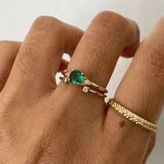 a woman's hand with a gold ring and green stone on it, next to her finger