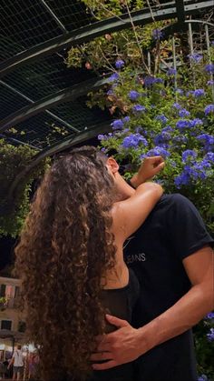 a man and woman standing next to each other in front of blue flowered trees