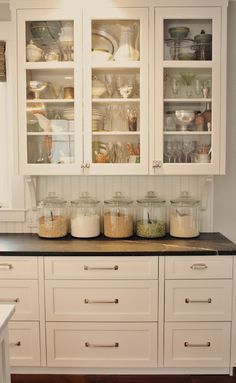 a kitchen with white cabinets and black counter tops