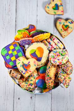 a bowl filled with lots of colorful cookies and sprinkles on top of a white wooden table