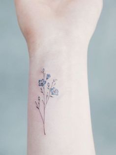 a small blue flower tattoo on the wrist