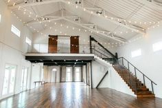 the inside of a large white building with wood floors and string lights hanging from the ceiling