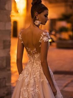 a woman in a wedding dress is standing on the street at night with her back to the camera