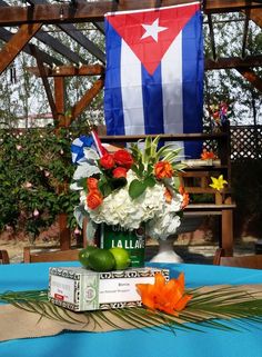 an arrangement of flowers and fruit on a table in front of a puerto rican flag