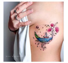 a woman's stomach with a small boat and flowers tattoo on her left side