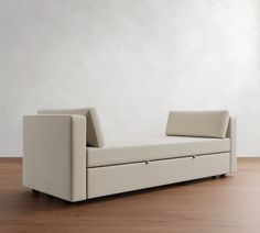 a white couch sitting on top of a wooden floor next to a wall and window