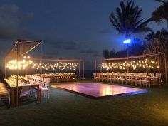 an outdoor wedding setup with lights on the dance floor and tables set up for dinner