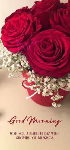 a bouquet of red roses sitting on top of a table next to a greeting card