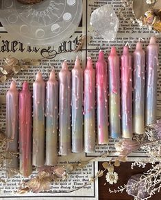 some pink and white candles on top of a newspaper