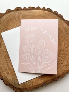 i love you mom card with pink flowers on it next to a piece of wood