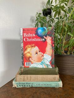 a stack of books sitting on top of a table next to a potted plant