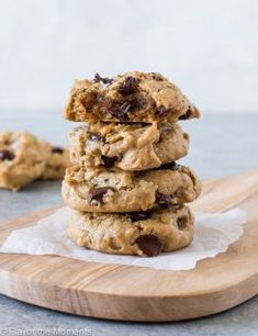 chocolate chip cookies stacked on top of each other in front of a wooden cutting board